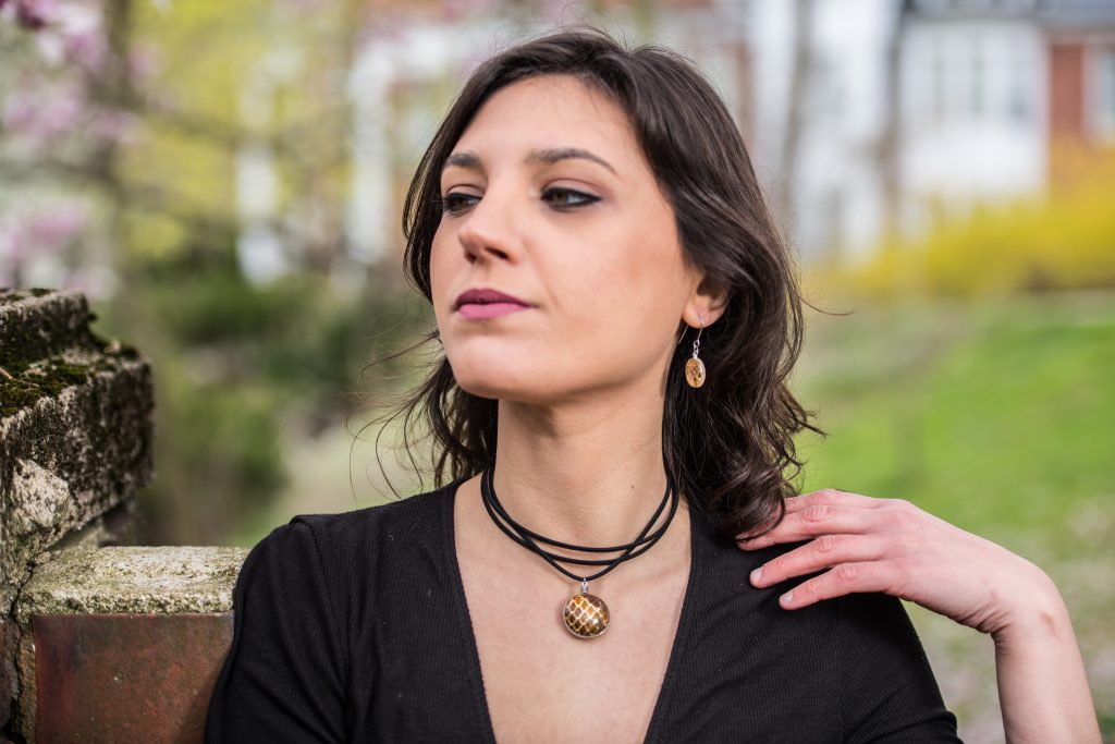 White girl with brown hair and a black shirt wearing a Shed Snakeskin & Gold Leaf Pendant on a black cord