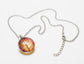 Gilded Poinsettia Pendant on a stainless steel chain laying on a white background