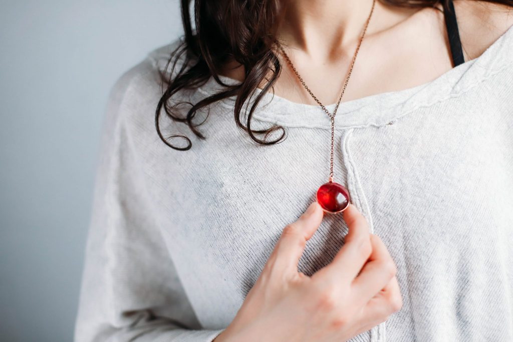 Close up of white girl with brown hair wearing a Rose Petal Pendant on a copper chain and a gray swewater