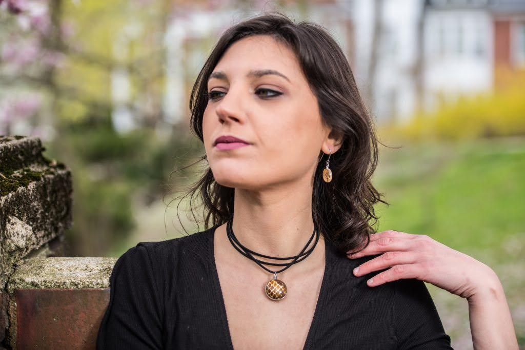 White girl with brown hair and a black shirt wearing a snake skin glass pendant on a 13" Stacked Faux Leather Choker