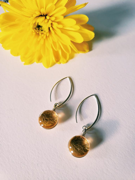 Sungold Dangle Earrings on a white background next to a yellow flower