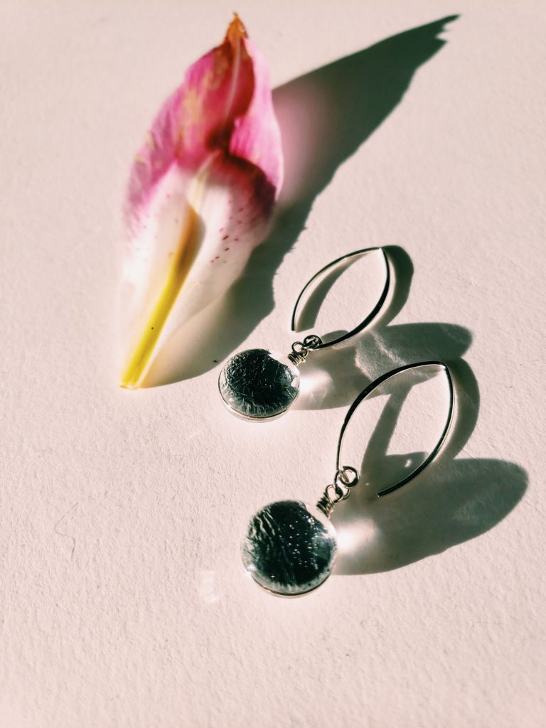 Silver Sungold Dangle Earrings on a white background next to a pink flower petal 