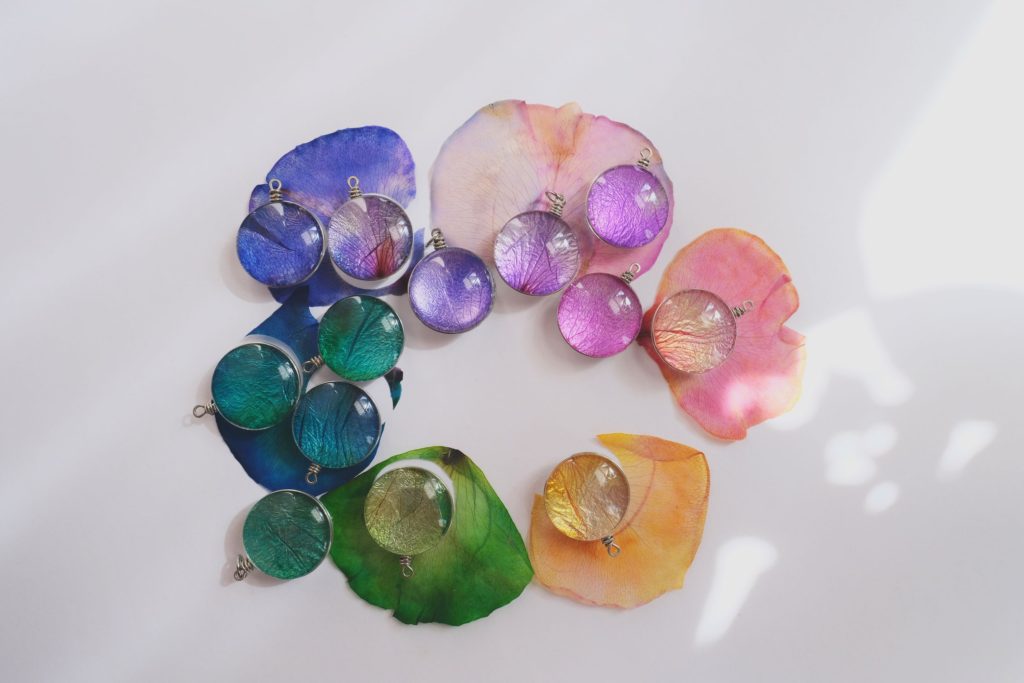 SisTers PGH Rainbow Rose Petal Pendants laying on their different colored rose petals 